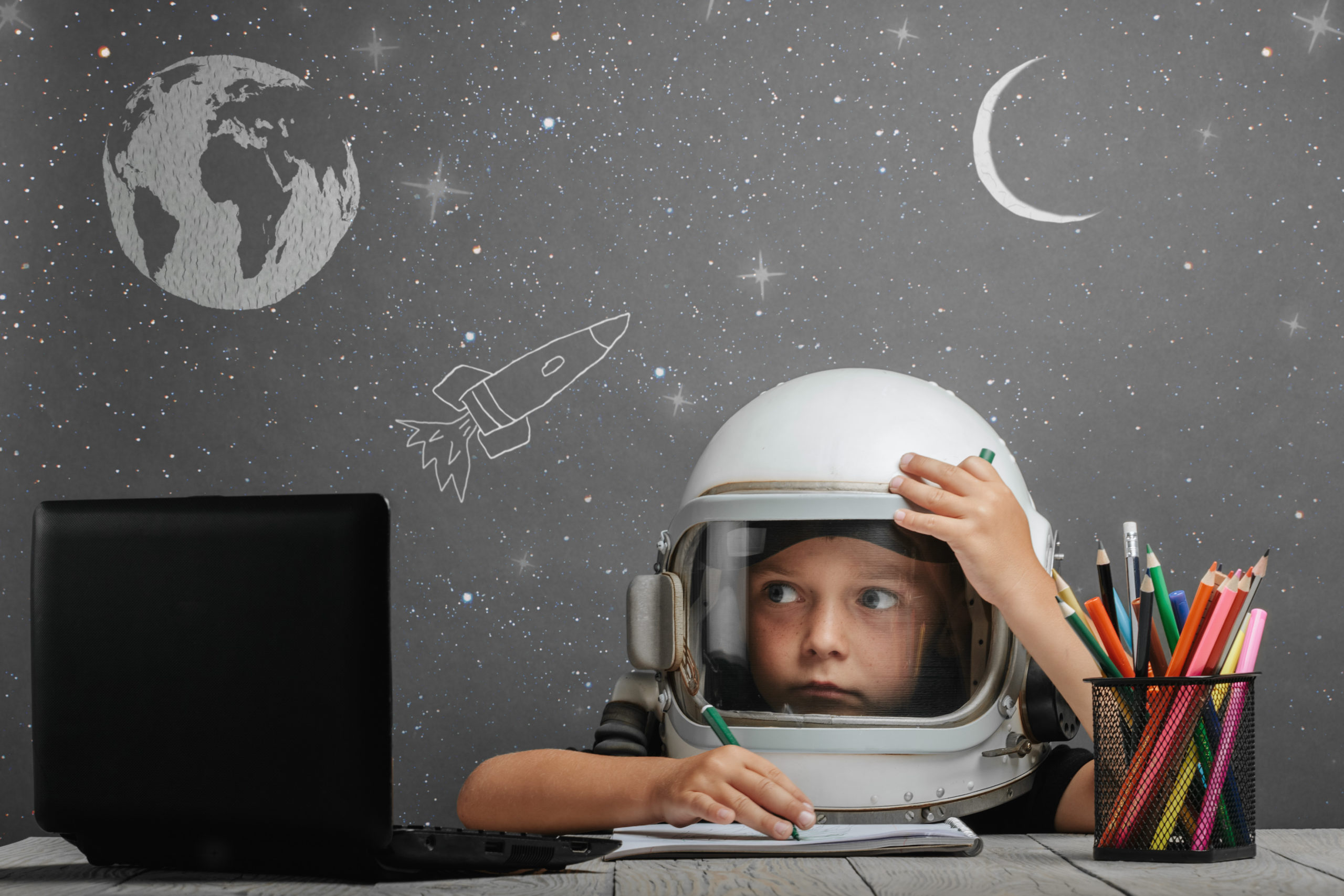 the child studies remotely at school, wearing an astronaut's hel